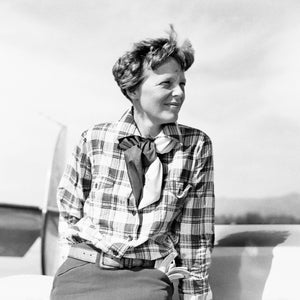 A picture of Amelia Earhart - stood by her plane in her checked shirt.