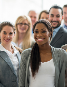 A group of workers smiling. The first being a woman in a grey cardigan, white top and long hair.