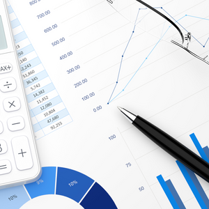 A pen and a calculator laying on sheets on charts and graphs