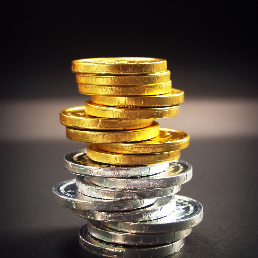 Gold and silver coins in a tower on the table with a black background. 