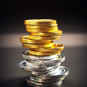 Gold and silver coins in a tower on the table with a black background. 