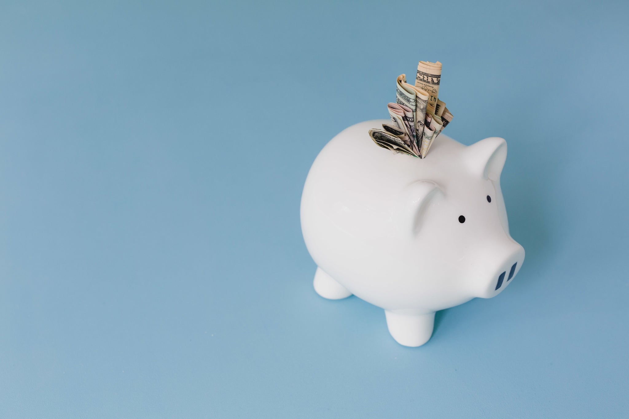 Piggy bank with a note sticking out. Blue background.