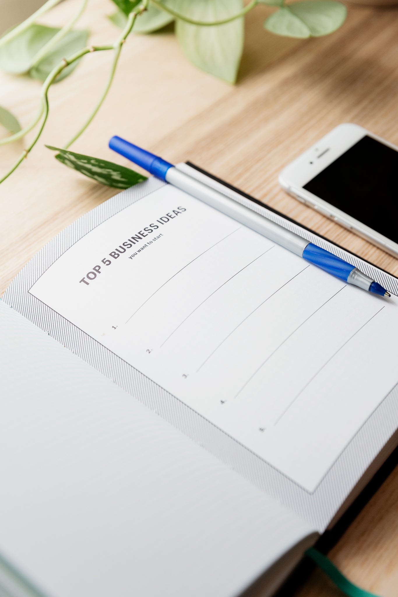 A picture of an open book with a 'to do list' on it, a blue pen and a phone on a wooden board.